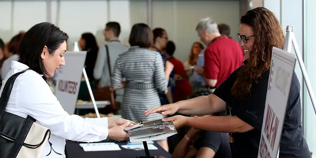 A conference participant receiving her nametag and a program.