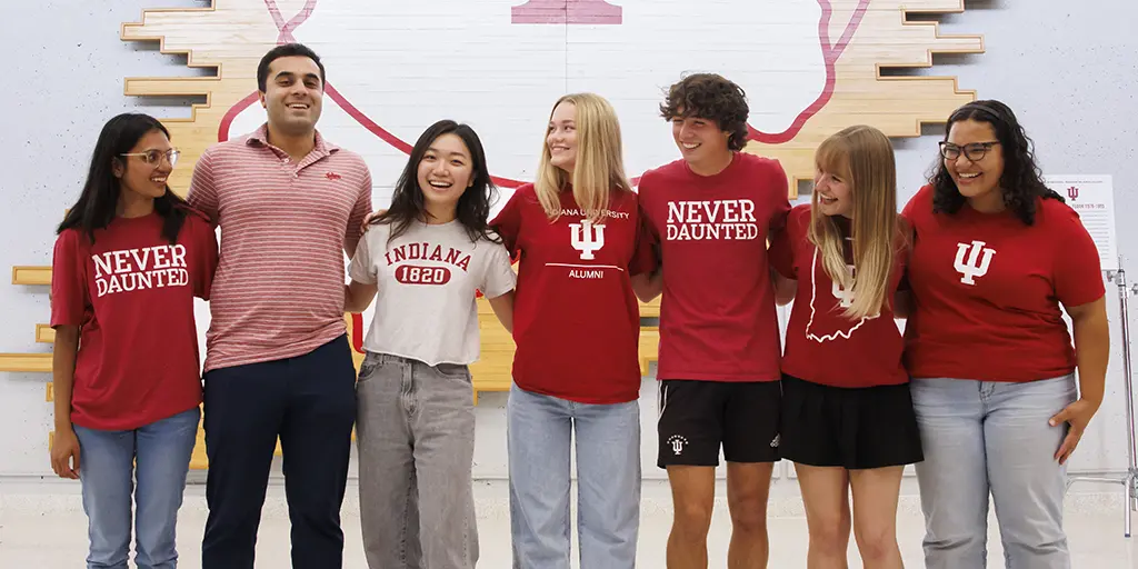 Students wearing IU t-shirts laugh while posing in a line for a picture.